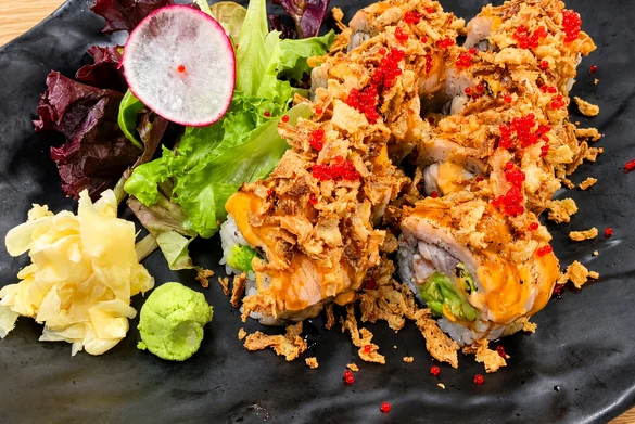 Double Salmon Roll with torched salmon, crispy onion and red tobiko, beside ginger, wasabi and salad